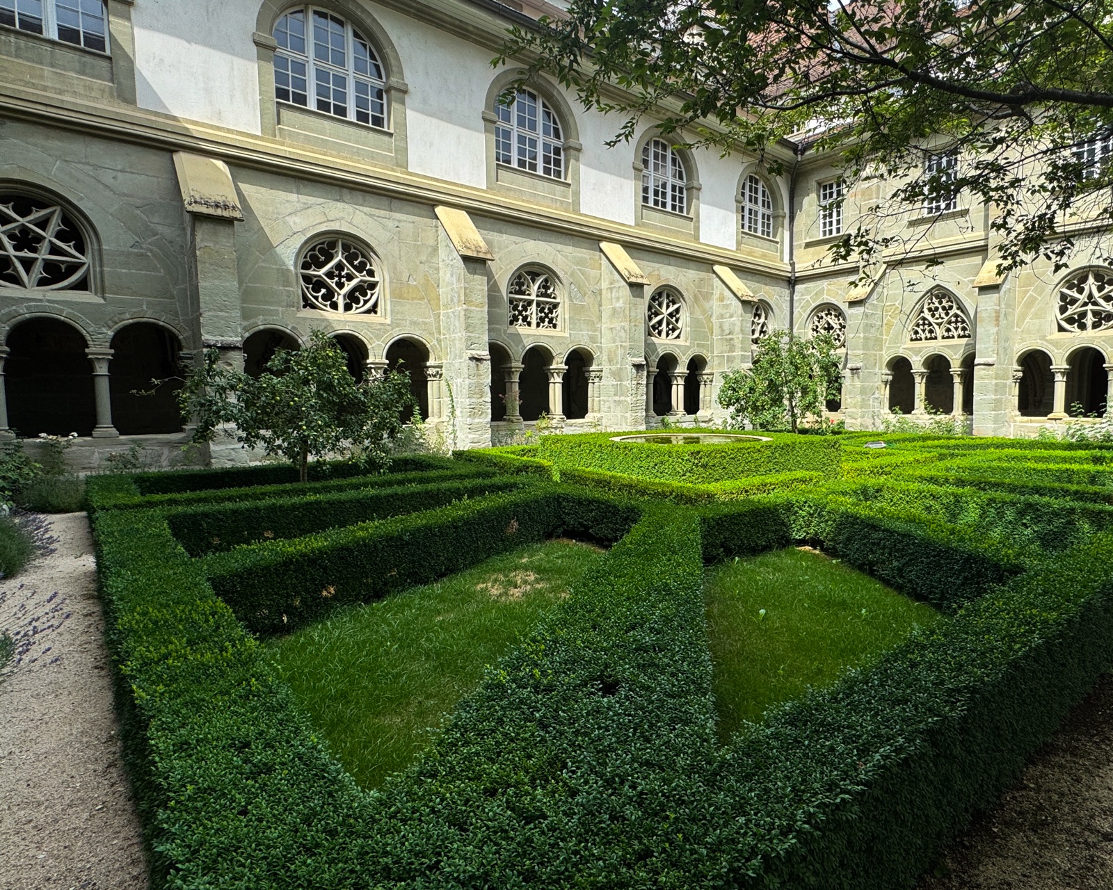 Kreuzgarten mit geschnittenen Buchshecken und Brunnen in der Mitte